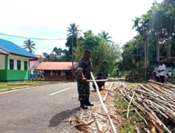 Babinsa dan Warga Bergotong Royong untuk Memperbaiki Kerapian Kampung dengan Membersihkan Kayu untuk Membuat Pagar