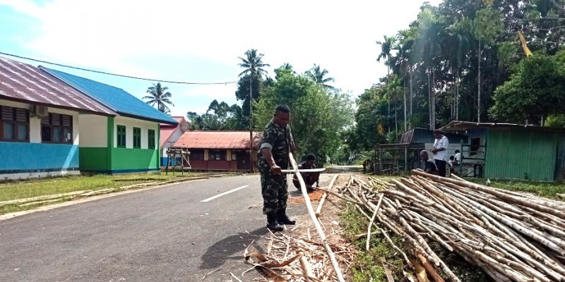 Babinsa dan Warga Bergotong Royong untuk Memperbaiki Kerapian Kampung dengan Membersihkan Kayu untuk Membuat Pagar