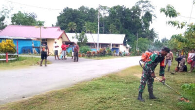 Babinsa Membantu Membersihkan Rumput dan Sampah di Bahu Jalan untuk Menciptakan Kemanunggalan TNI-Rakyat