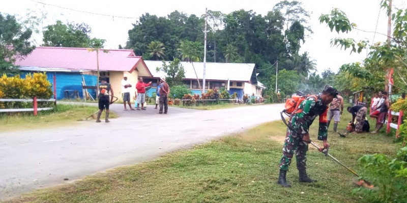 Babinsa Membantu Membersihkan Rumput dan Sampah di Bahu Jalan untuk Menciptakan Kemanunggalan TNI-Rakyat