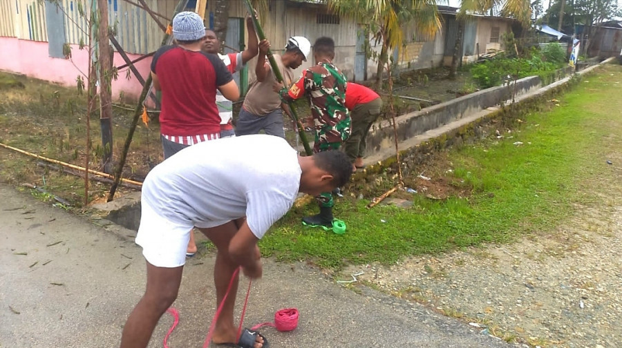 Babinsa membantu warga memasang lampu-lampu Natal di Jalan Desa Fanindi menjelang Natal